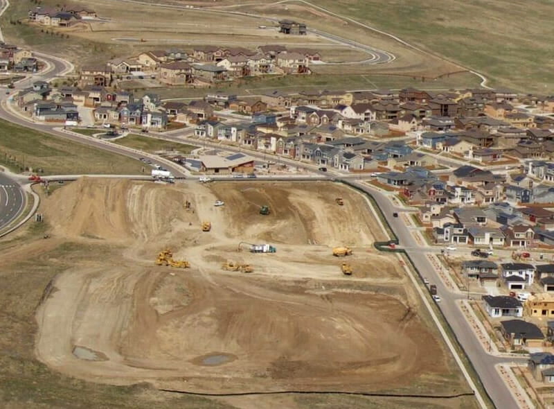 view of a large work site with many homes in the distance