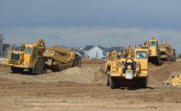 three tractors on a dirt work site