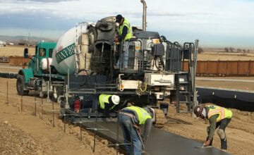 cement truck with men smoothing a concrete slab